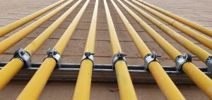 Well-maintained yellow gas pipes parallel on side of building